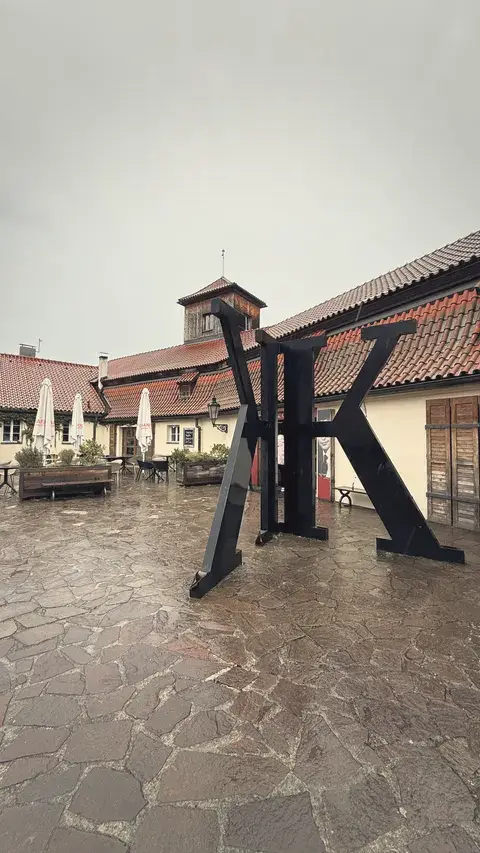卡夫卡博物館門口那個巨大的 K，在雨裡很像小說封面。