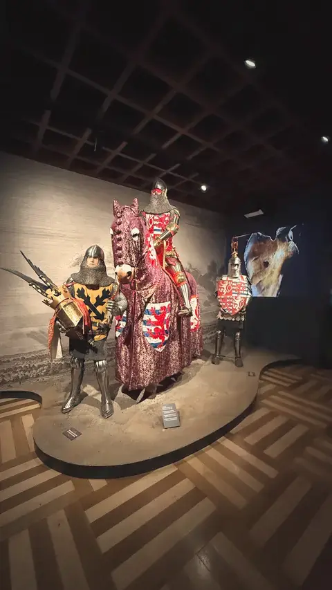 騎士和披著紋章布的戰馬，站在人字拼木地板上。