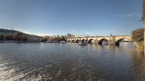 從河岸看查理大橋，水面亮晶晶的。