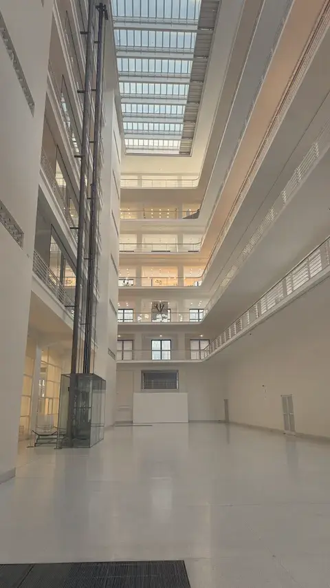 貿易宮的中庭：一層一層白色迴廊，頭上是整片天窗。